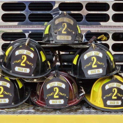 Fire helmets with 'Ypsilanti' and number '2' on a metal rack.