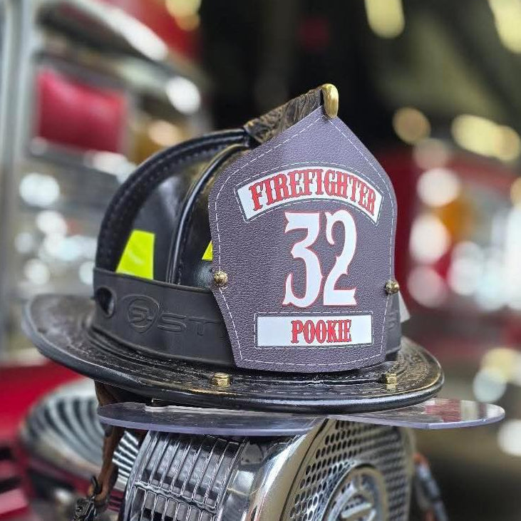 Firefighter helmet with the number 32 on a fire truck background
