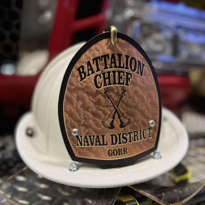 Hard hat with 'Battalion Chief Naval District GORR' plaque on a blurred background