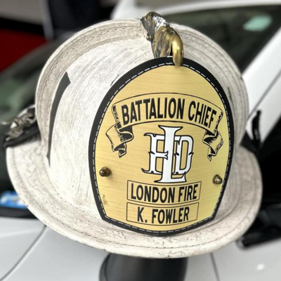 Firefighter helmet with 'Battalion Chief' badge attached to a vehicle