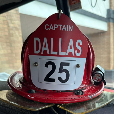 Red fire helmet with 'Captain Dallas 25' on a vehicle dashboard