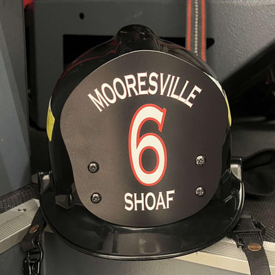 Black helmet with 'Mooresville 6 Shoaf' text on a vehicle interior.